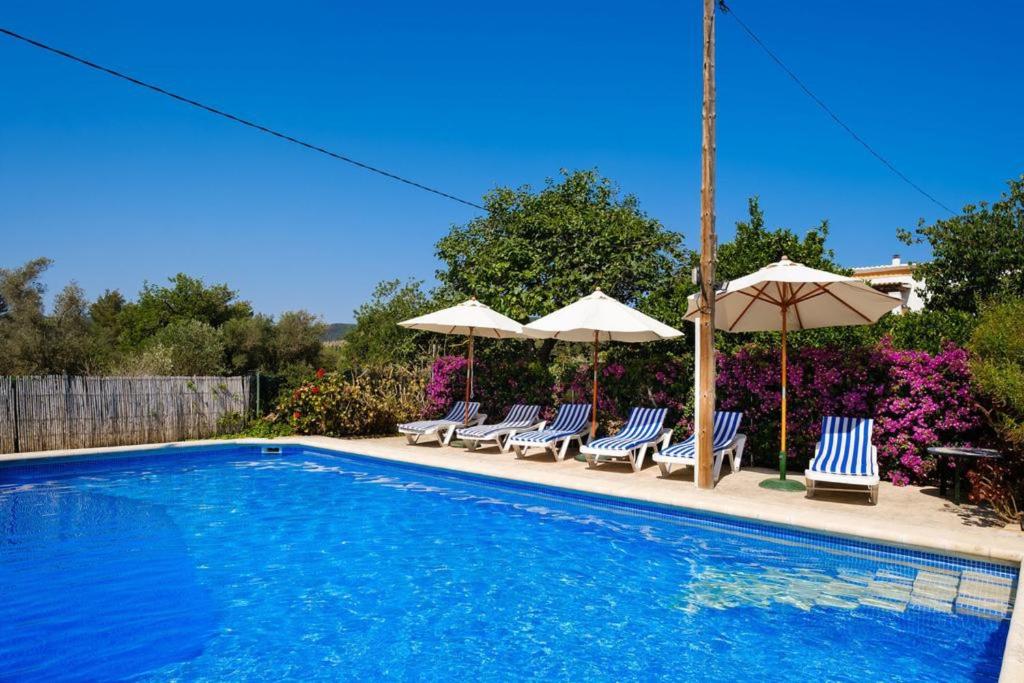 a swimming pool with lounge chairs and umbrellas at 4 bedrooms villa with private pool enclosed garden and wifi at Sant Miquel de Balansat 5 km away from the beach in Sant Miquel de Balansat