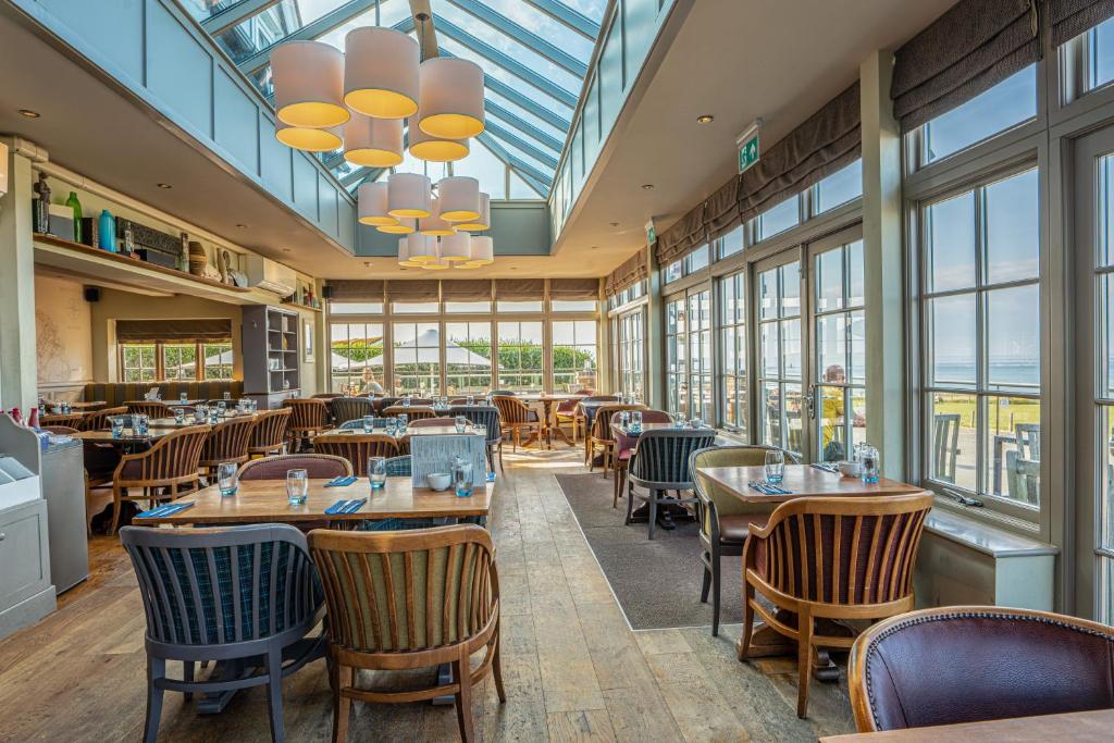 a restaurant with tables and chairs and windows at Botany Bay Hotel in Broadstairs