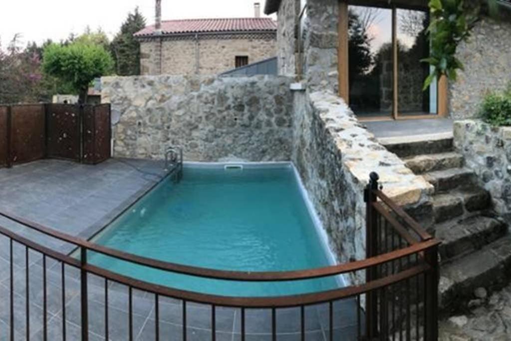 a hot tub in a stone wall with a fence at Gîte Le Pilat in Vernoux-en-Vivarais