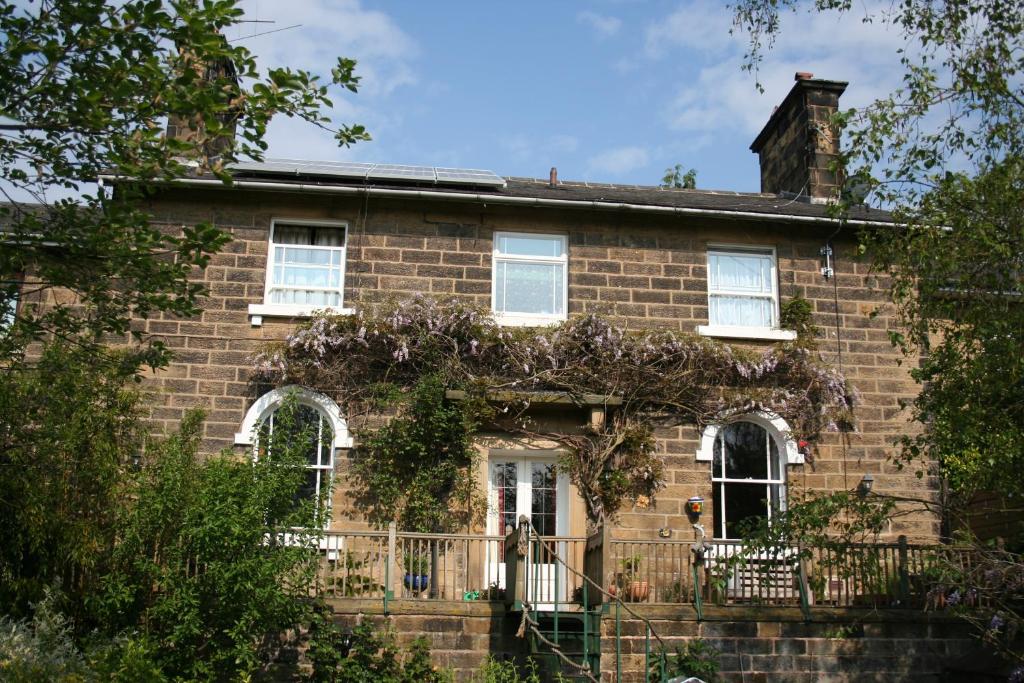 uma velha casa de tijolos com uma cerca em frente em The Old Station House em Matlock