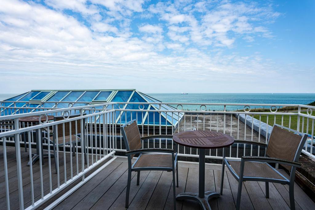 a balcony with two chairs and a table and the ocean at Botany Bay Hotel in Broadstairs