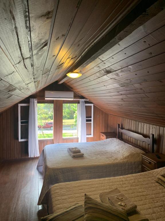 a bedroom with two beds and a large window at HMG Morada & Chalet - Centro histórico in Petrópolis