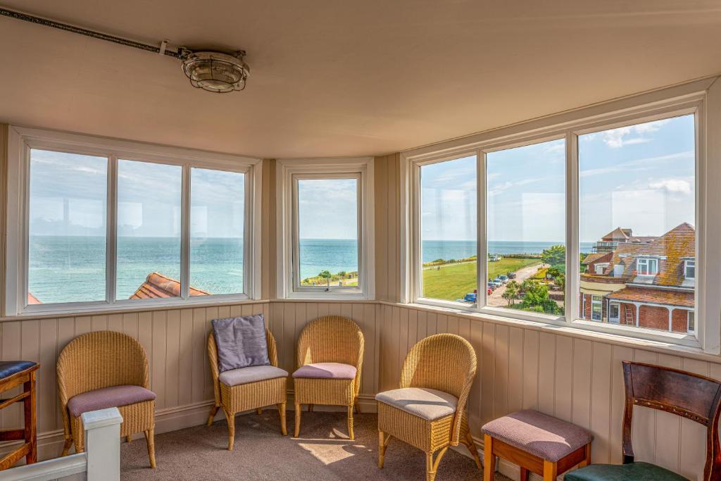 a waiting room with chairs and windows overlooking the ocean at Botany Bay Hotel in Broadstairs