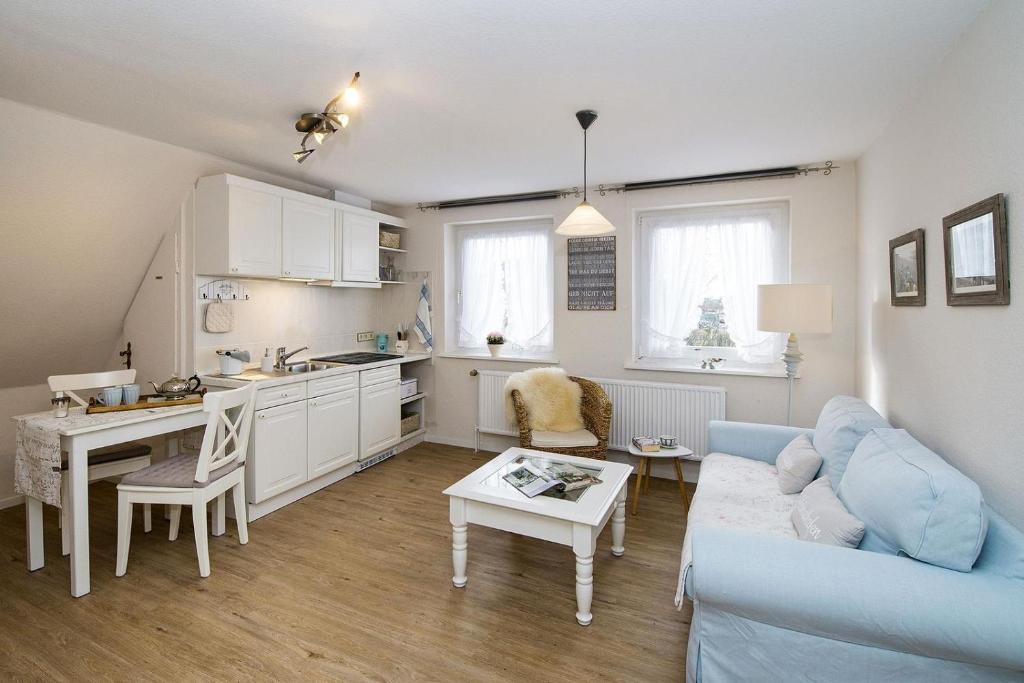 a living room with a blue couch and a kitchen at Strandläufernest in Tinnum