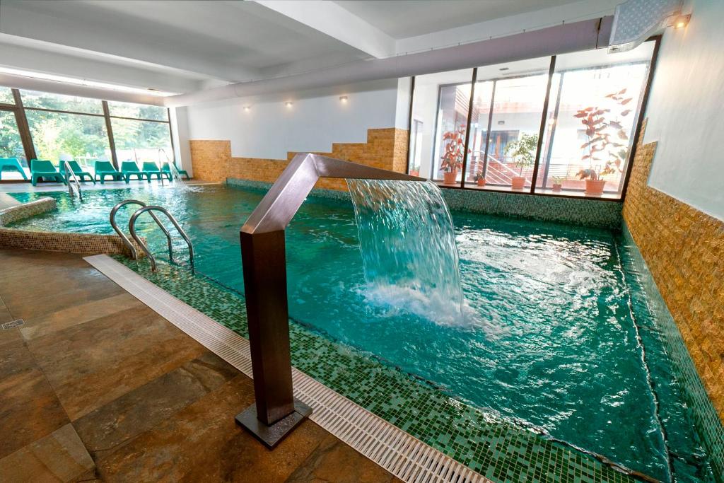 a swimming pool with a waterfall in a hotel room at Hotel Tisa in Băile Olăneşti