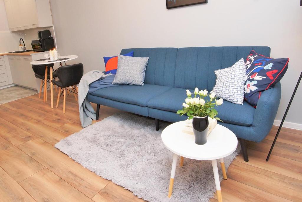 Loft Apartament 1 في جورزو فيلكوبولسكي: غرفة معيشة مع أريكة زرقاء وطاولة