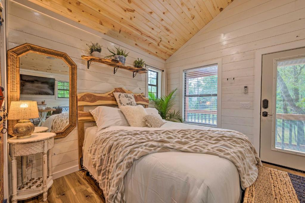 a bedroom with a bed and a mirror at Charming Broken Bow Cabin with Jacuzzi and Fire Pit! in Broken Bow