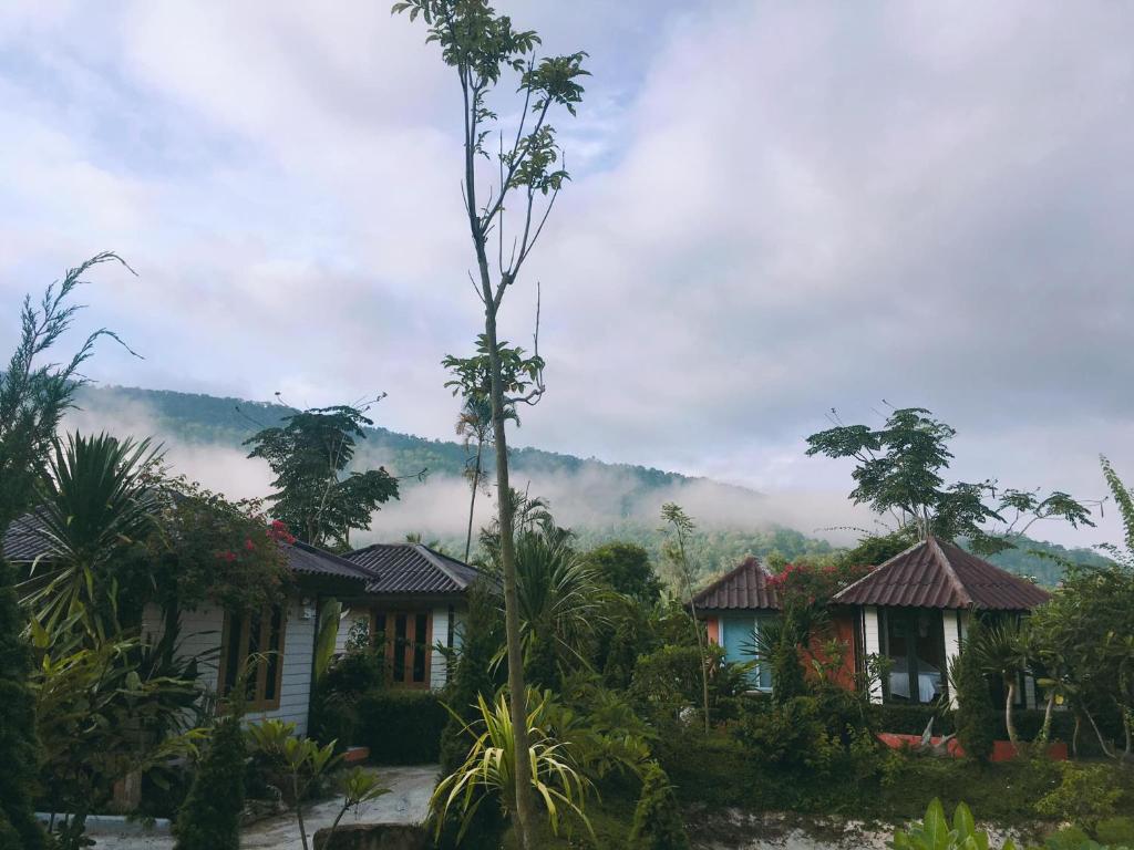 uma árvore em frente a uma casa com montanhas ao fundo em ชมวิว รีสอร์ท em Loei