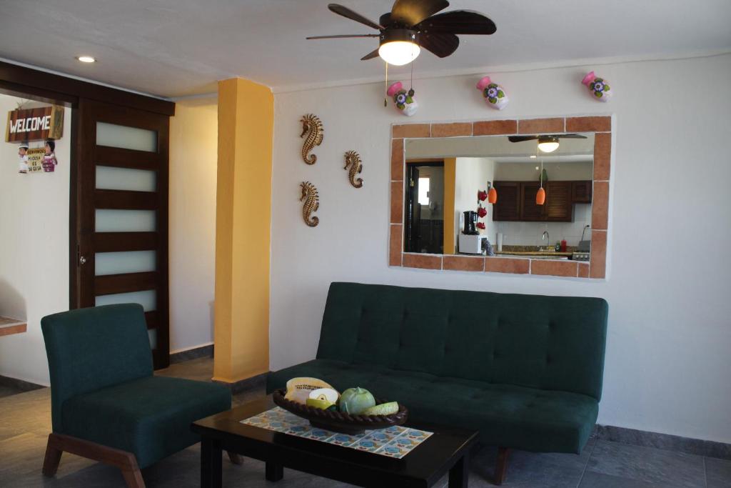 a living room with a green couch and a chair at Cande's Apartments in Isla Mujeres