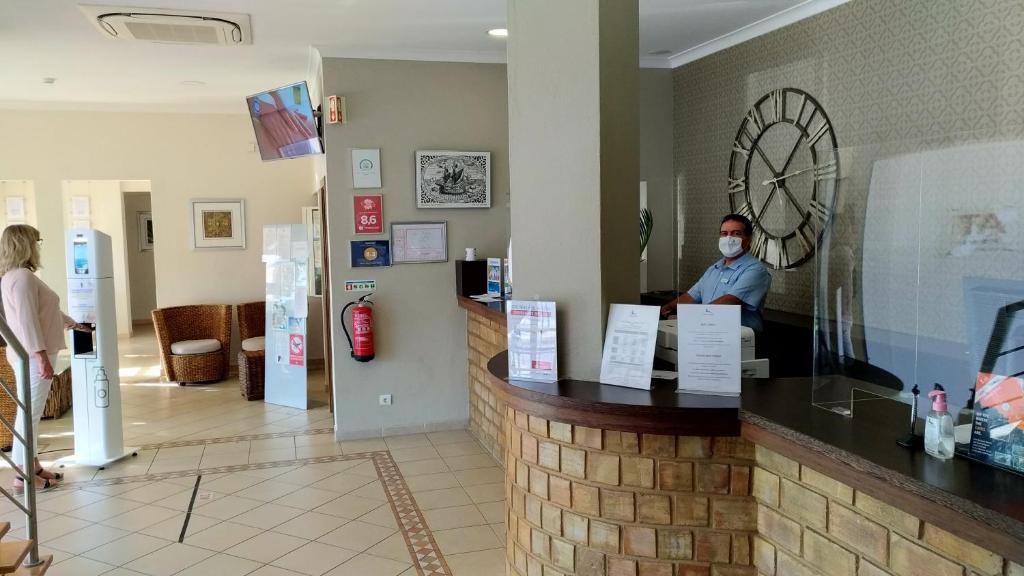 a man in a mask sitting at a counter in a restaurant at Rocha Brava Village Resort in Carvoeiro