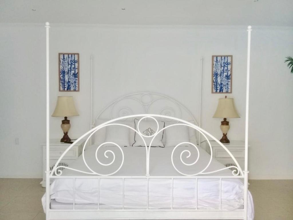 a white bed in a white room with two lamps at Ocean Front Property - Villa 4 Aruba w pool view in Savaneta