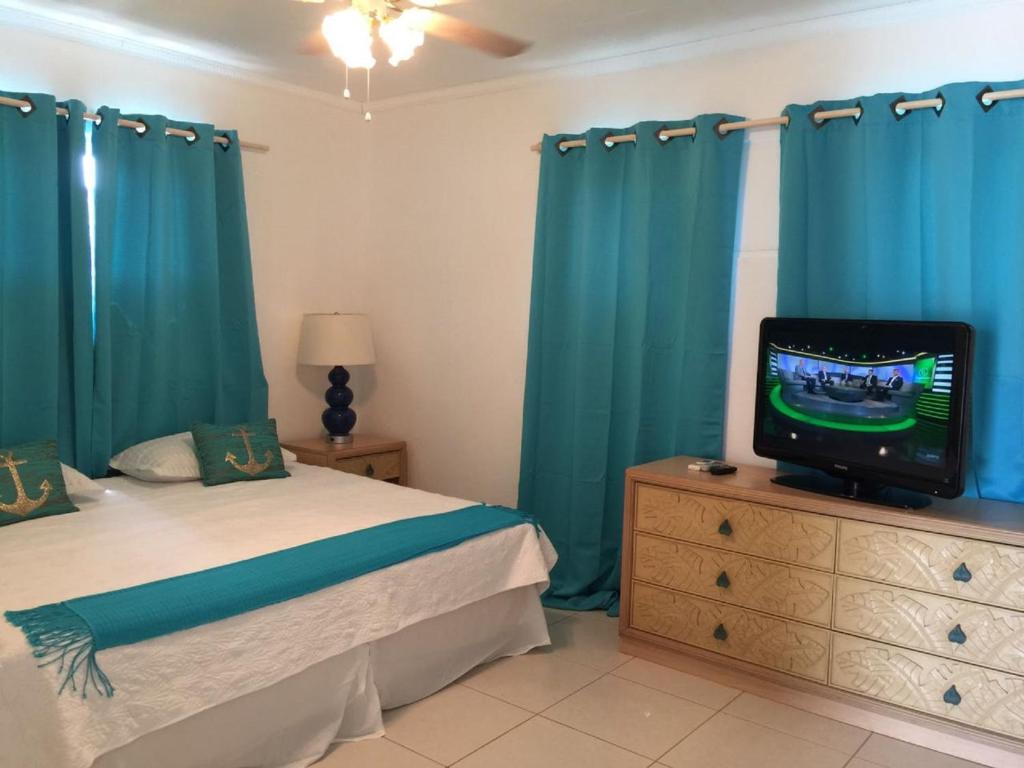 1 dormitorio con cama y vestidor con TV en Opa sml Cute beach apartment, en Savaneta