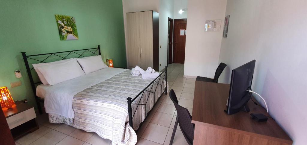 1 dormitorio con 1 cama y escritorio con TV en Costa Gaia Rooms, en San Vito lo Capo