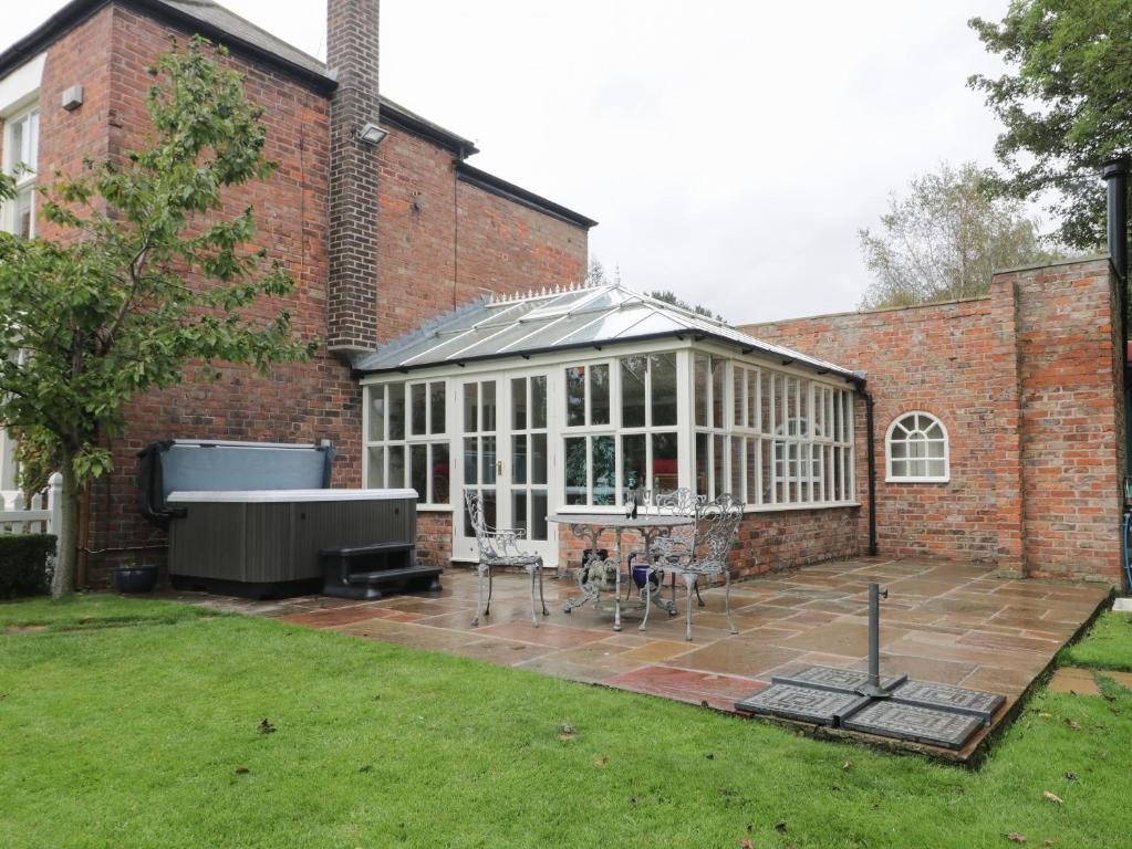 a brick building with a greenhouse in a yard at Ash Tree Lodge in Hull