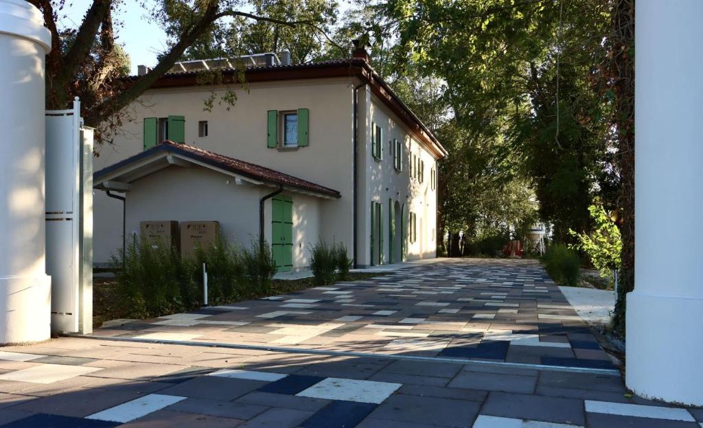 a white building with green doors on a street at Villa Il Selvatico in San Giorgio di Piano