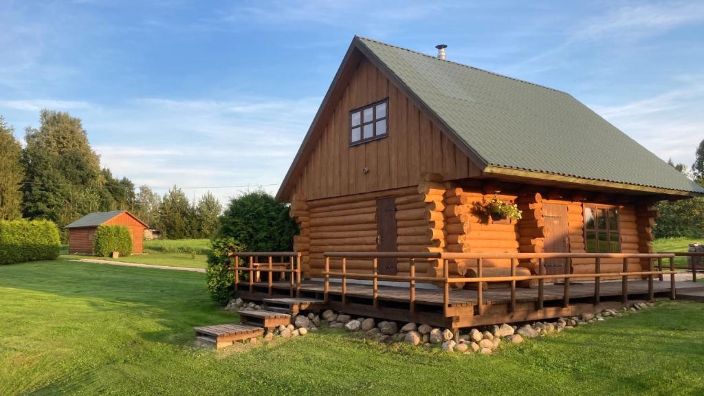 uma cabana de madeira com um telhado de gambrel e um alpendre em Tatra Holiday House em Tatra