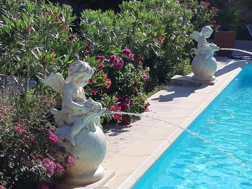 une statue d'anges assise sur un vase à côté d'une piscine dans l'établissement LES CHAMBRES MANON - Piscine, Spa, Tennis, à Belcodène