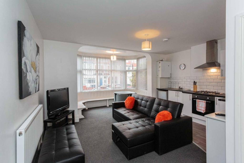 a living room with a leather couch and a tv at Cherry Property - Orange Suite in Blackpool