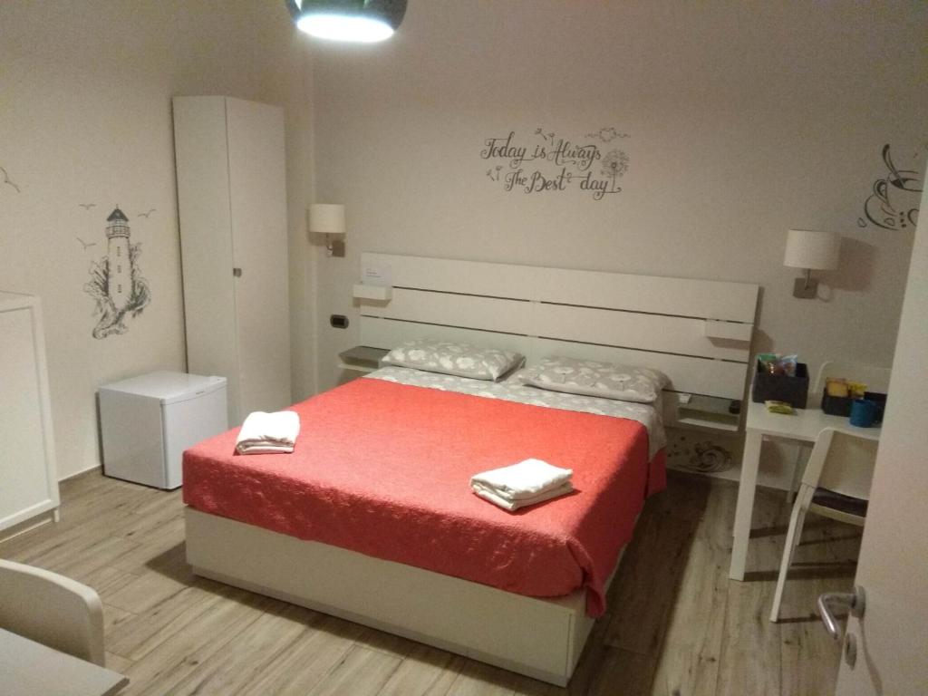 Schlafzimmer mit einem Bett mit roter Bettwäsche und Handtüchern in der Unterkunft Blue Rose Private Room in Salerno