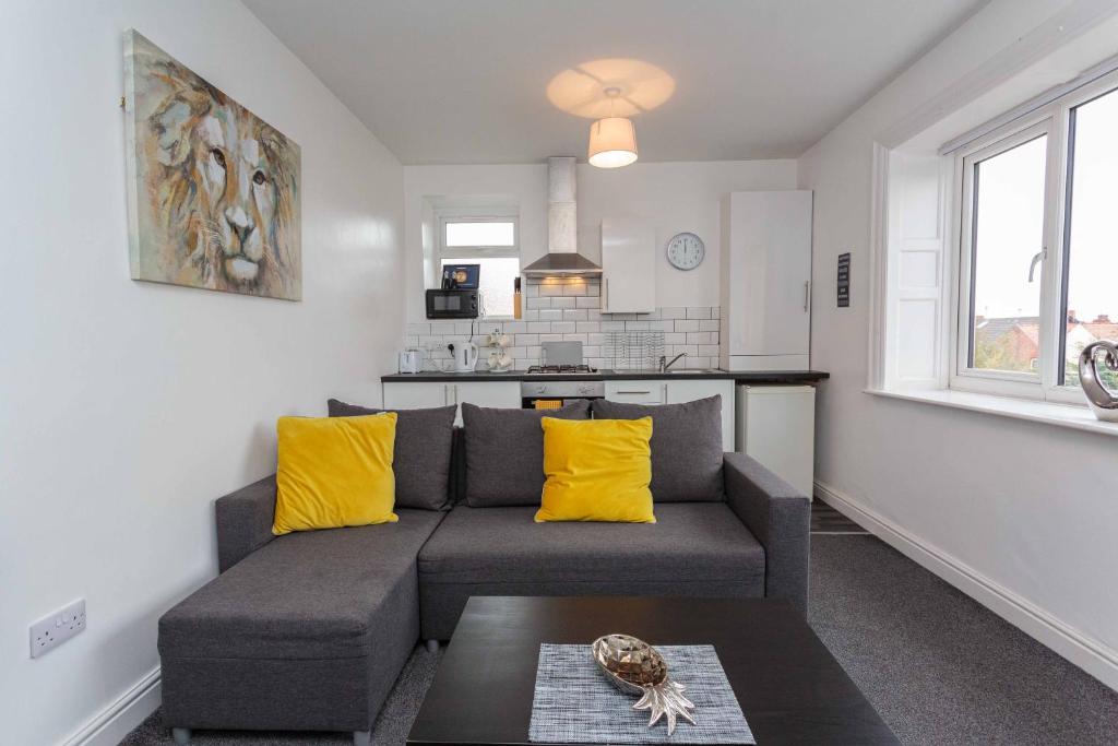 ein Wohnzimmer mit einem grauen Sofa und gelben Kissen in der Unterkunft Cherry Property - Pineapple Suite in Blackpool