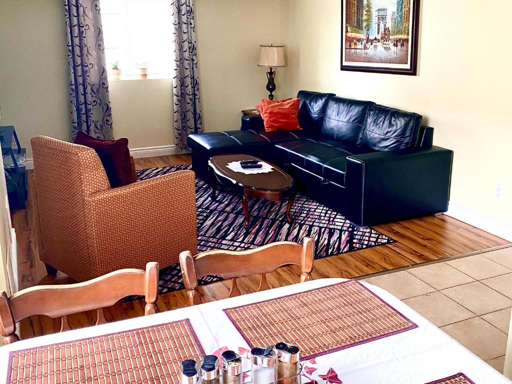 una sala de estar con un sofá de cuero negro y sillas en Elgin Suite, en Niagara Falls