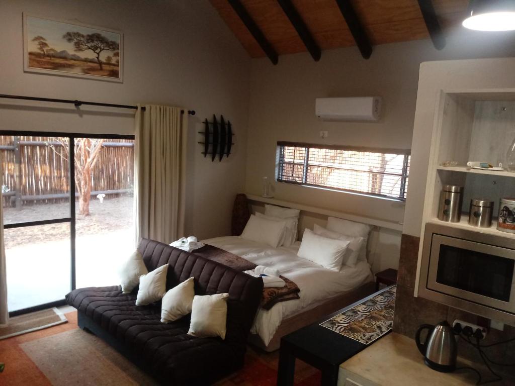 a living room with a couch and a bed at Marloth Wild Fig Studio in Marloth Park