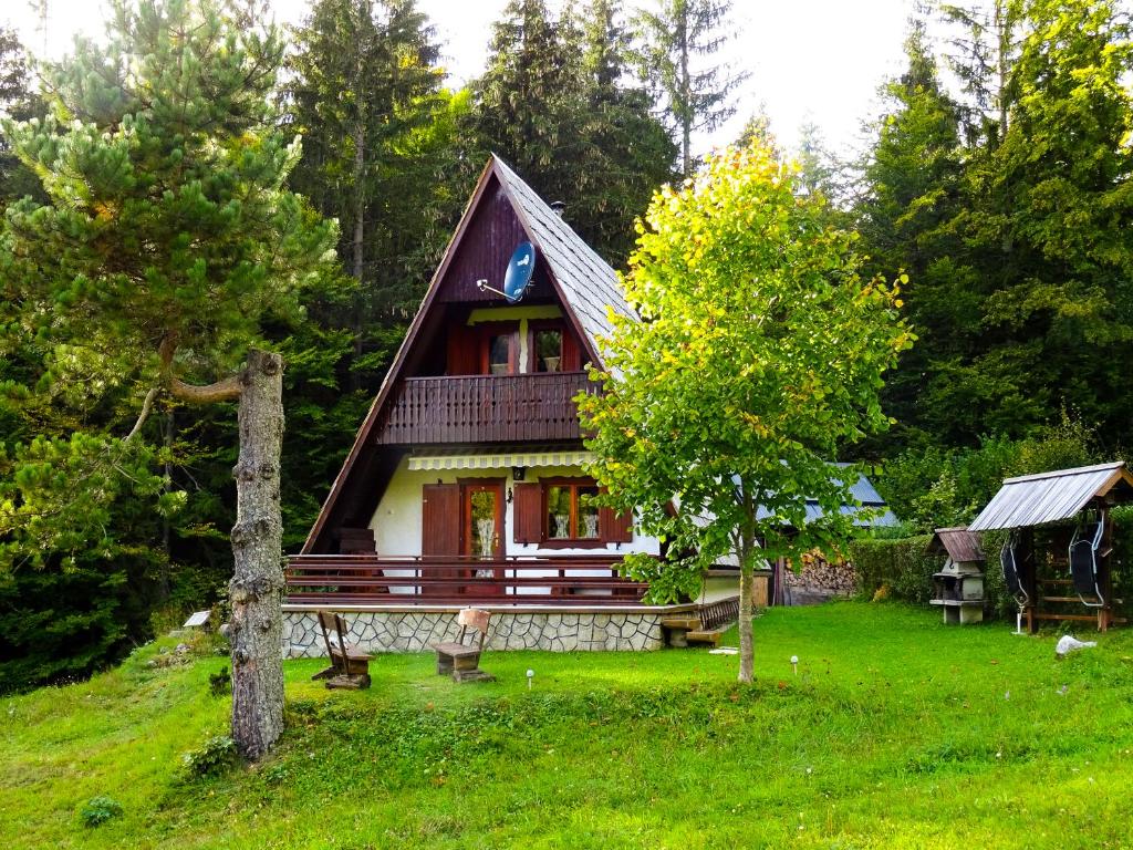 une petite maison avec un banc dans l'herbe dans l'établissement Wooden Cottage, à Jesenice