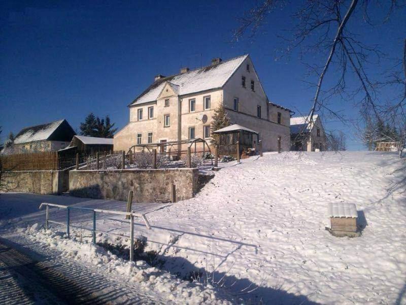 um grande edifício na neve em frente a uma casa em Dom O Niebieskich Okiennicach em Gryfów Slaski