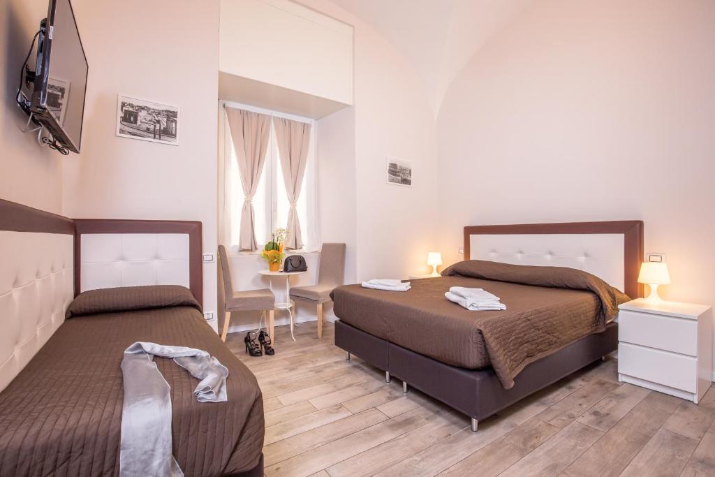 a bedroom with two beds and a table and a desk at Azzurra Rooms in Rome