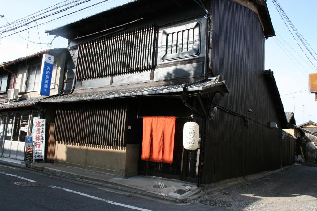 Guesthouse KYOTO COMPASS في كيوتو: مبنى أسود مع منشفة برتقالية معلقة على الباب