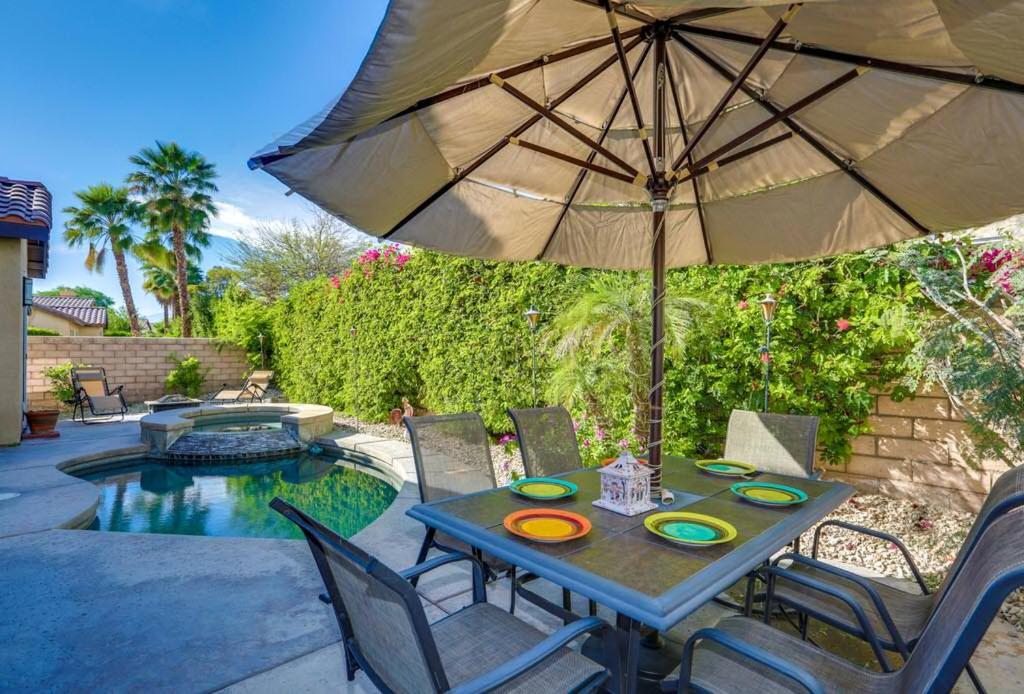 a table with an umbrella next to a pool at Indian Palms Vacation Villa Permit# 50273 in Indio