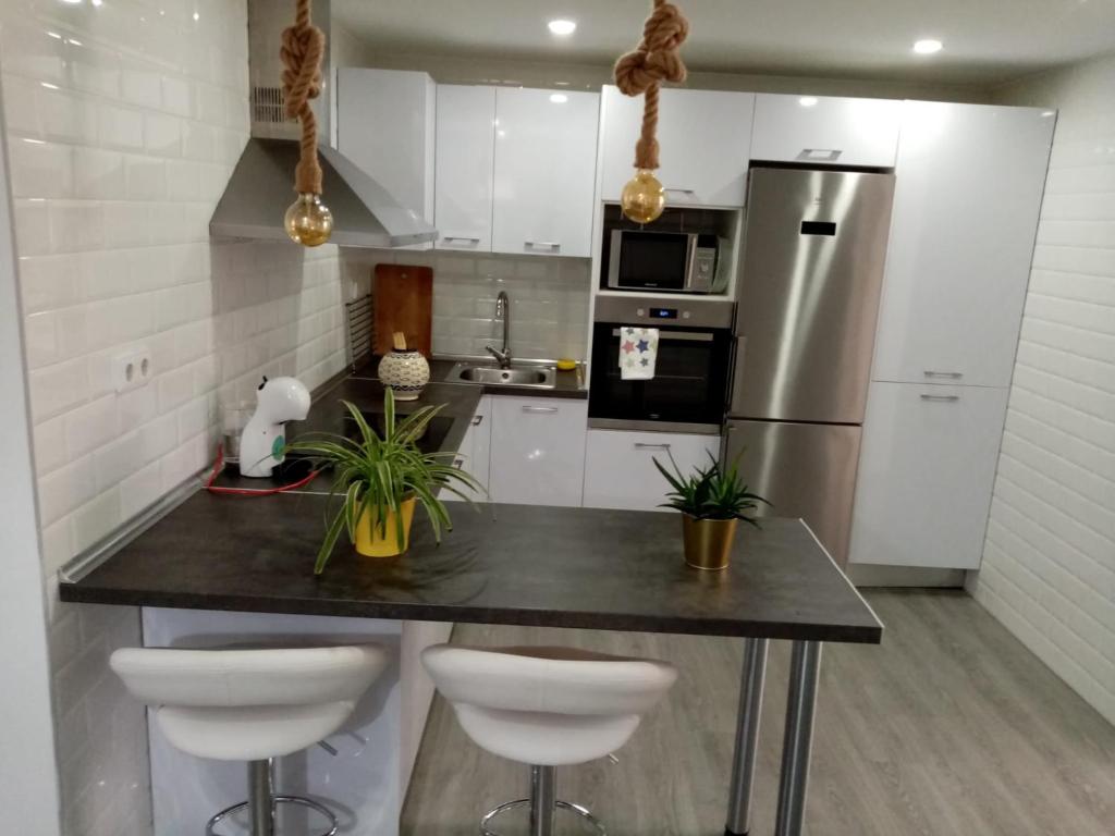 a kitchen with a counter with stools and a refrigerator at Apartamento céntrico recién reformado in Murcia