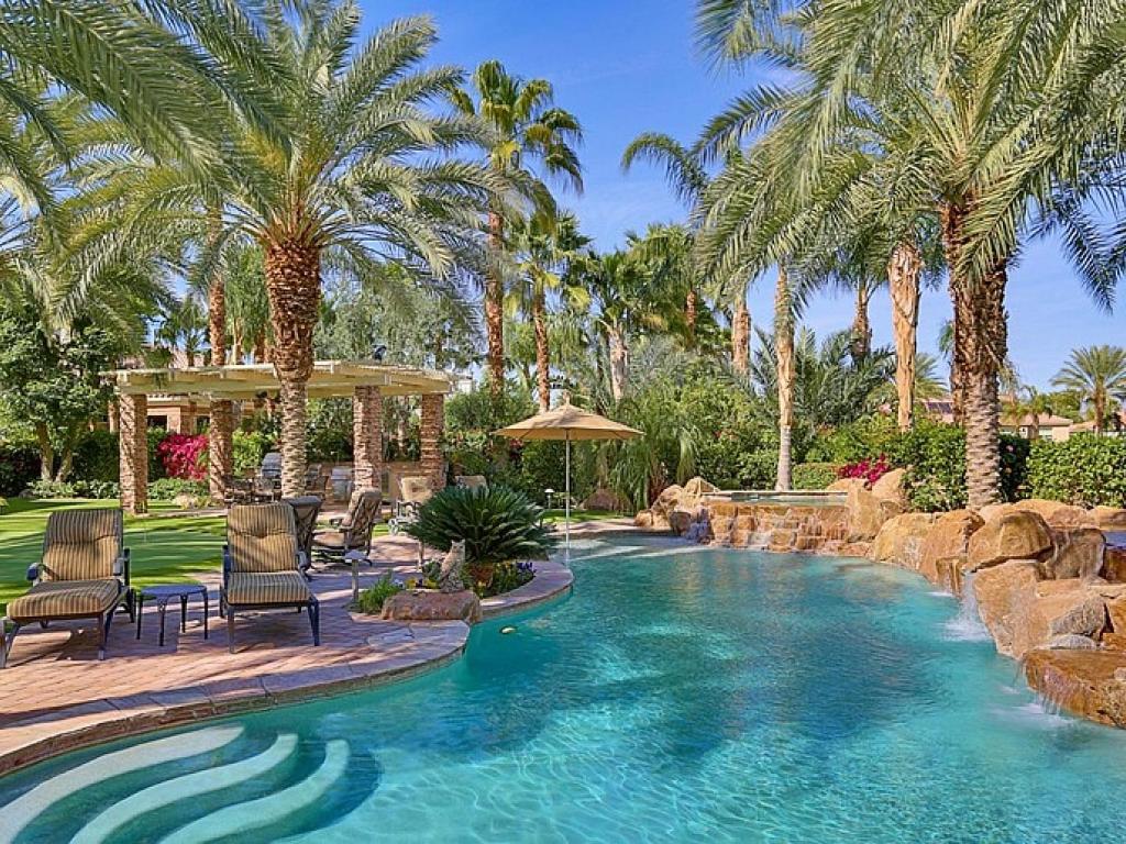 a swimming pool with palm trees in a resort at Legends Retreat Permit# 110,800 in La Quinta