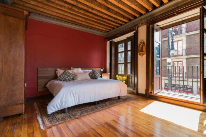 a bedroom with a bed with red walls and windows at CASA SAUTO Suite Cathedral Views in Downtown in Mexico City