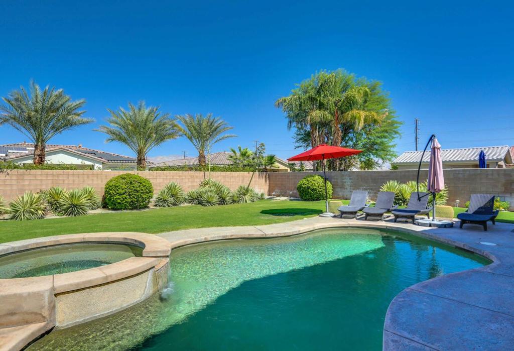 een zwembad met 2 stoelen en een parasol bij Tranquil Times in Palm Desert