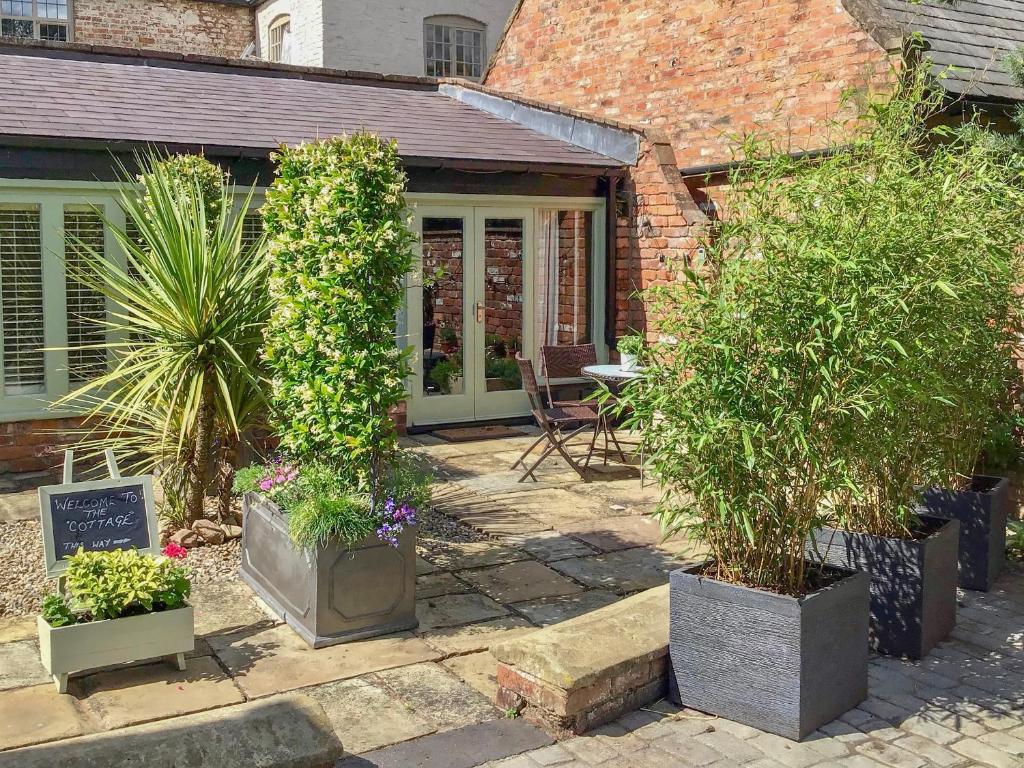 a garden with potted plants in front of a building at The Cottage The Coach House in Wrexham