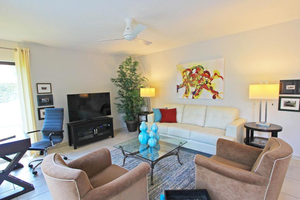 ein Wohnzimmer mit einem weißen Sofa und einem TV in der Unterkunft Sagewood Views in Palm Springs