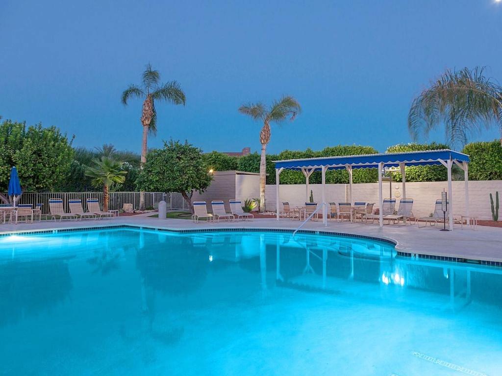 a large blue swimming pool with chairs and palm trees at Plaza Villa Downtown Condo Permit# 2877 in Palm Springs