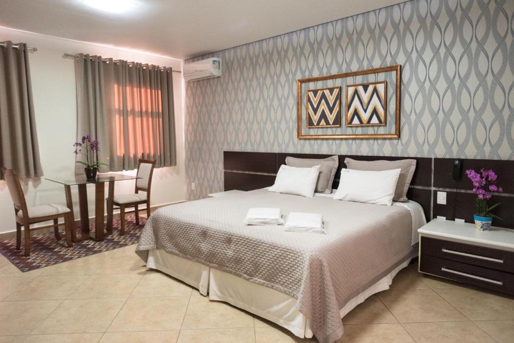 a bedroom with a large bed and a dining room at Holambra Garden Hotel in Holambra