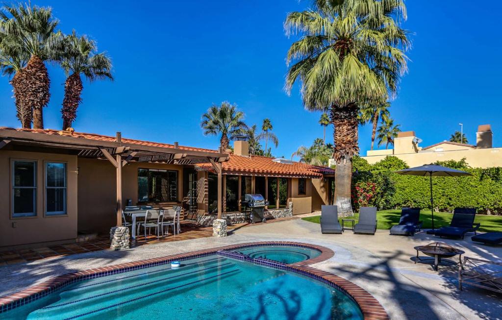 a house with a swimming pool and palm trees at Spanish Hideaway Permit# 4007 in Palm Springs