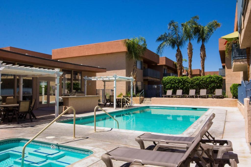 einen Pool mit Chaiselongues neben einem Gebäude in der Unterkunft Palm Springs Sunrise Condo in Palm Springs