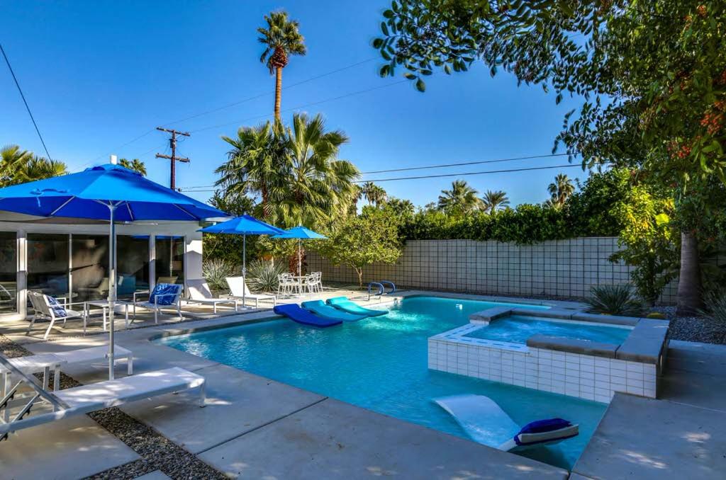 a swimming pool with chairs and umbrellas at Riviera Palm Springs Permit# 2044 in Palm Springs