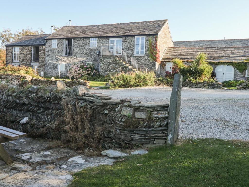 una casa de piedra con una valla de piedra delante de ella en Threshings Cottage en Tintagel