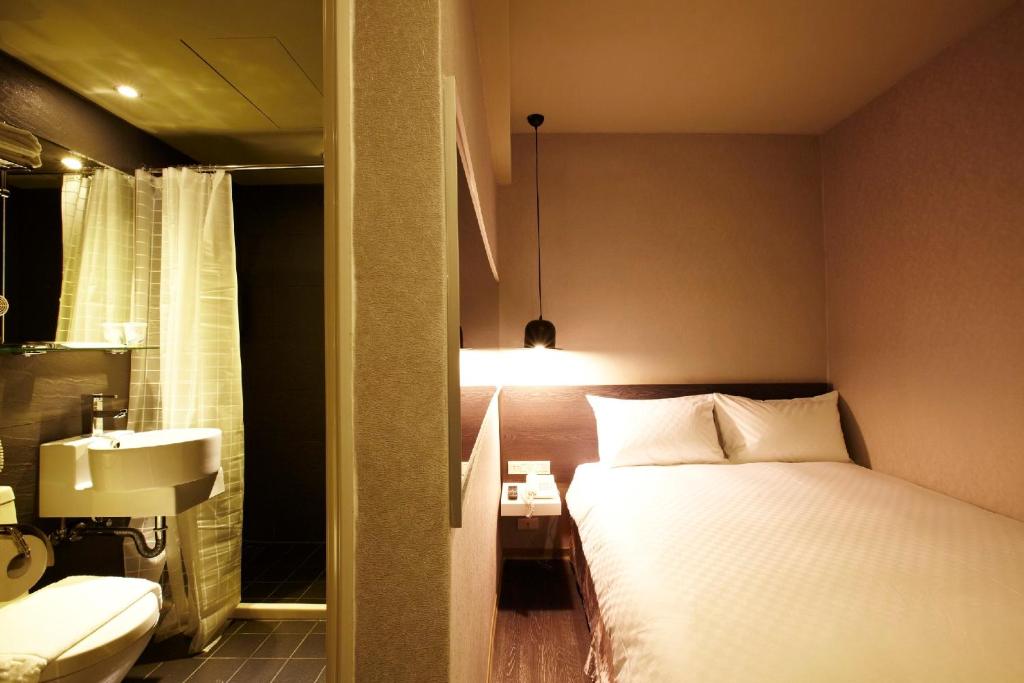 ein Schlafzimmer mit einem Bett und ein Badezimmer mit einem Waschbecken in der Unterkunft Main Inn Taipei in Taipeh