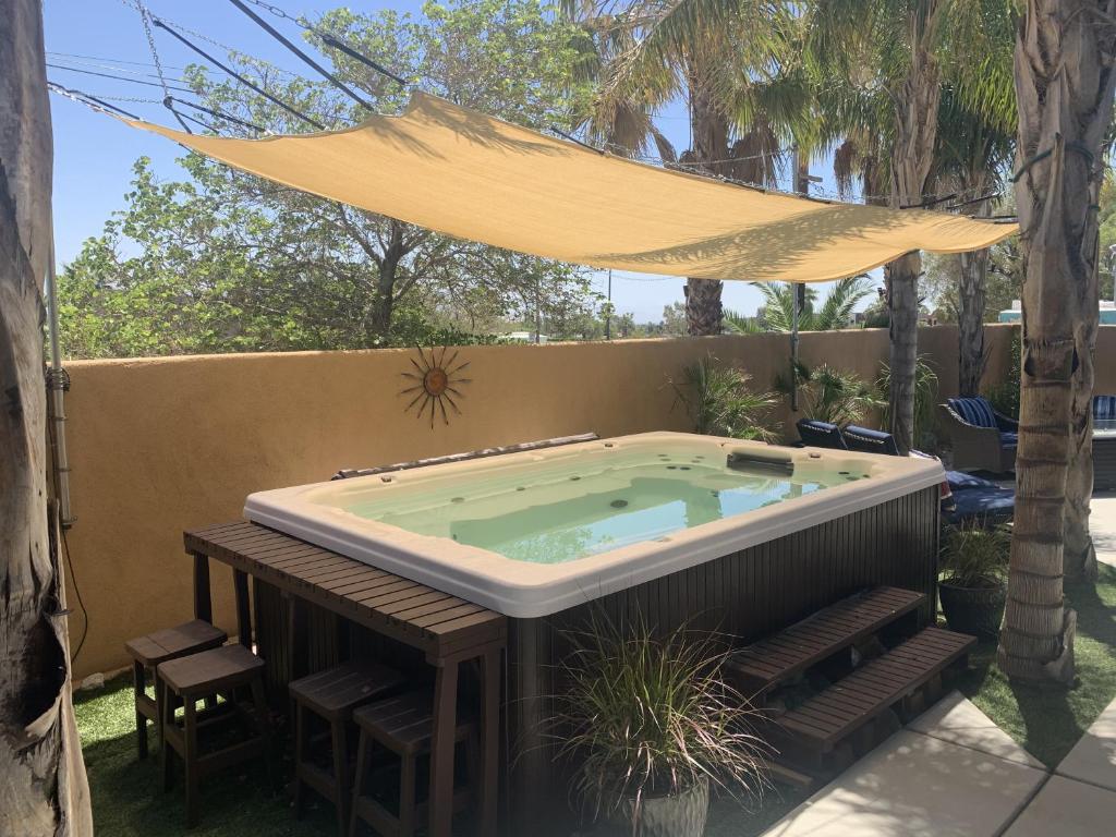 una bañera de hidromasaje en un patio trasero con sombrilla en Villa Callejon Del Sol Permit# 3082 en Palm Springs