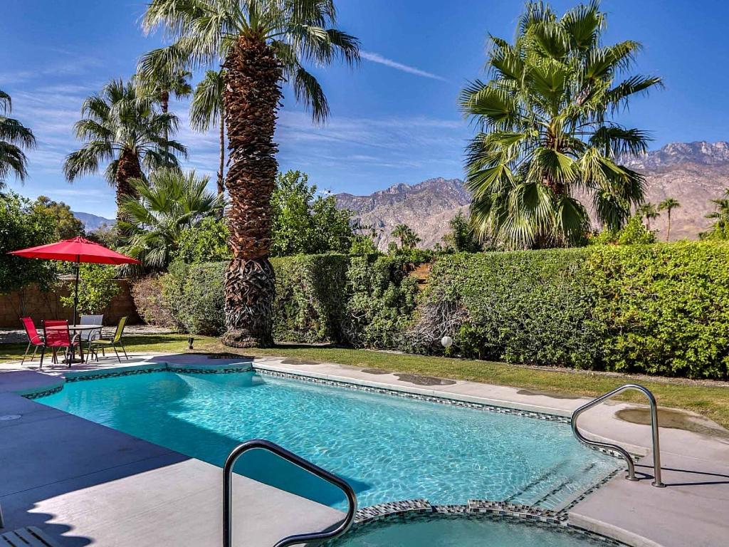 a swimming pool in a yard with palm trees at Orchid Tree Villa Permit# 2244 in Palm Springs