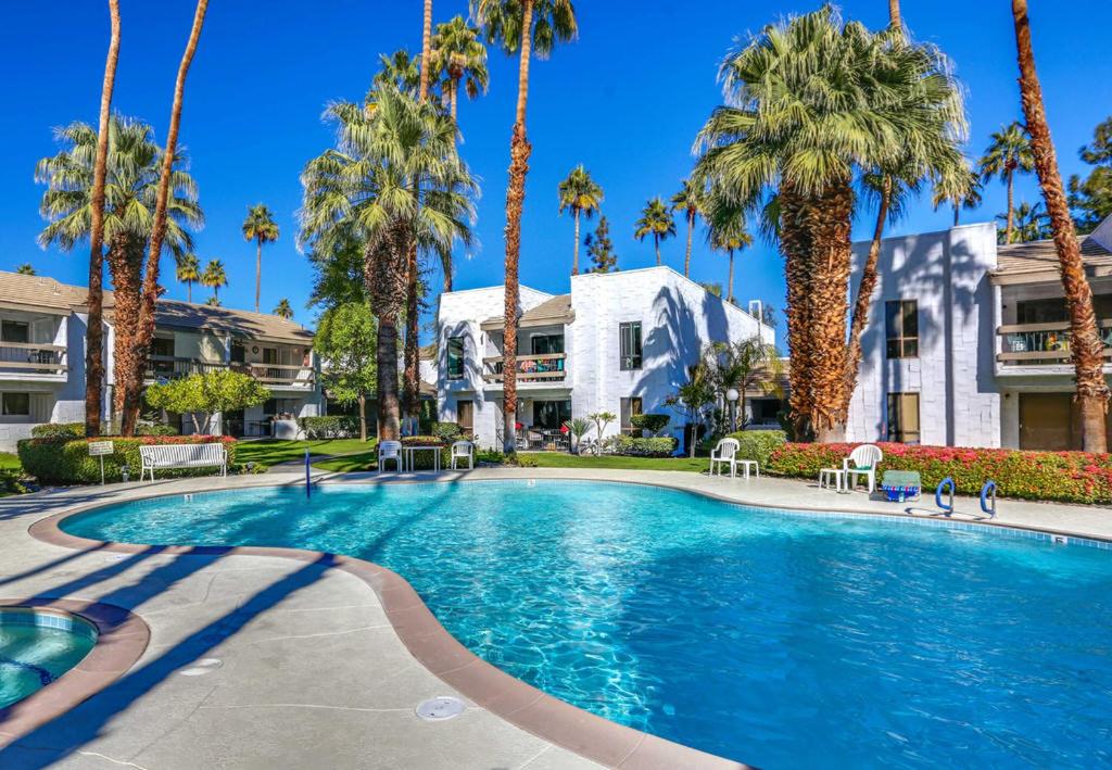 a swimming pool with palm trees in front of a building at Waverly Vacation Condo Permit# 4210 in Palm Springs