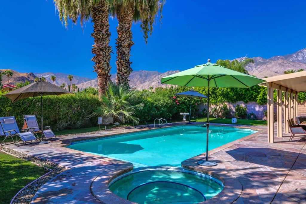 - une piscine avec un parasol vert et des palmiers dans l'établissement My Palm Springs Place Permit# 3042, à Palm Springs