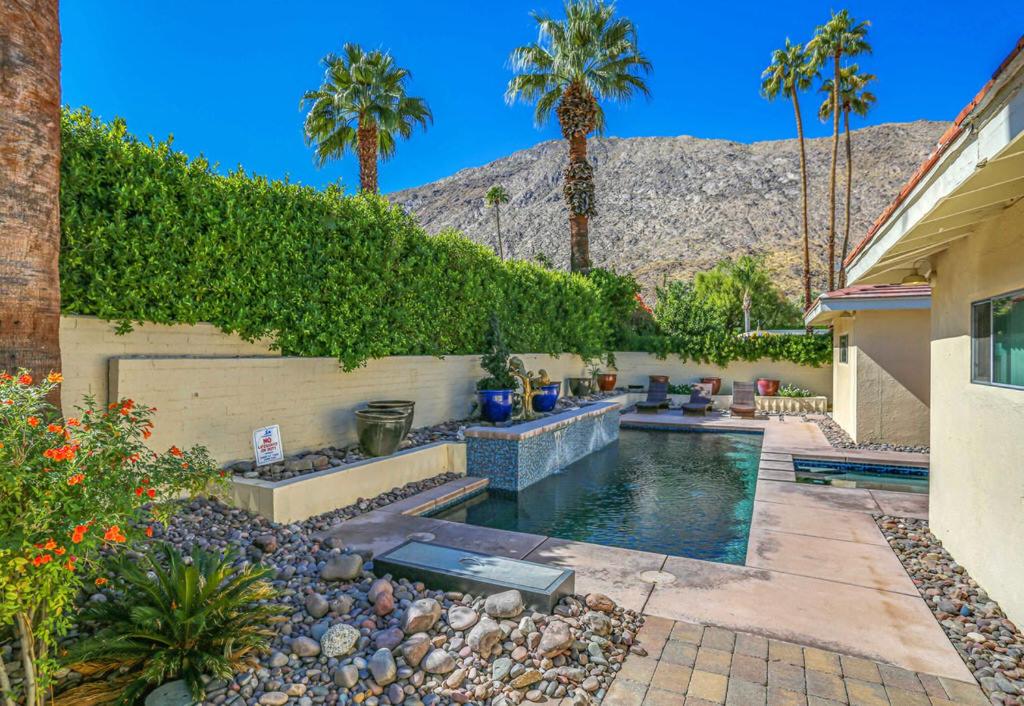 a backyard with a swimming pool and palm trees at Historic Tennis Club Cody Permit# 3344 in Palm Springs