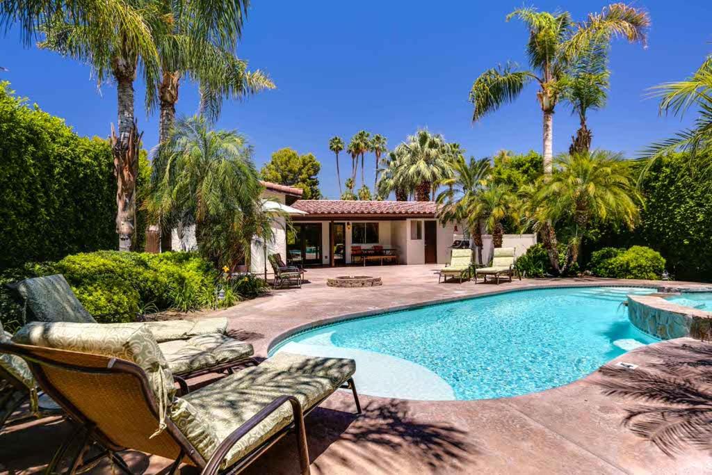 uma piscina com cadeiras e uma casa com palmeiras em Poolside Terrace Permit# 1786 em Palm Springs